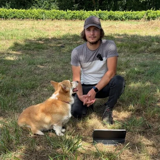 Éducateur canin avec son chien, un corgi, pendant une séance d’éducation en plein air.
